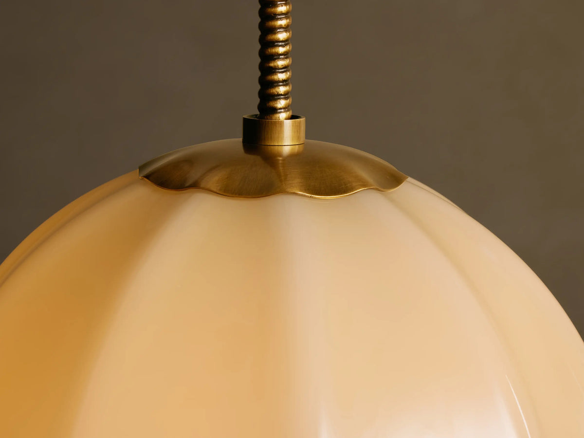 Close-up of the Agnes pendant scalloped antique brass fitting and paneled cream glass shade