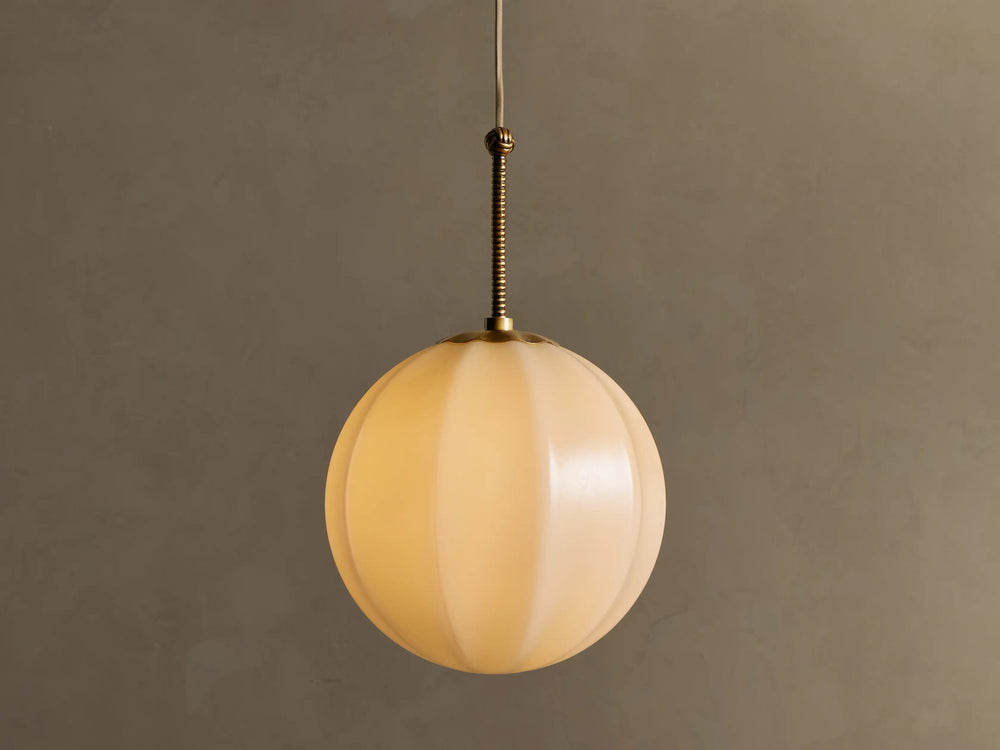 Agnes 12-inch pendant illuminated with a paneled cream glass globe and antique brass stem