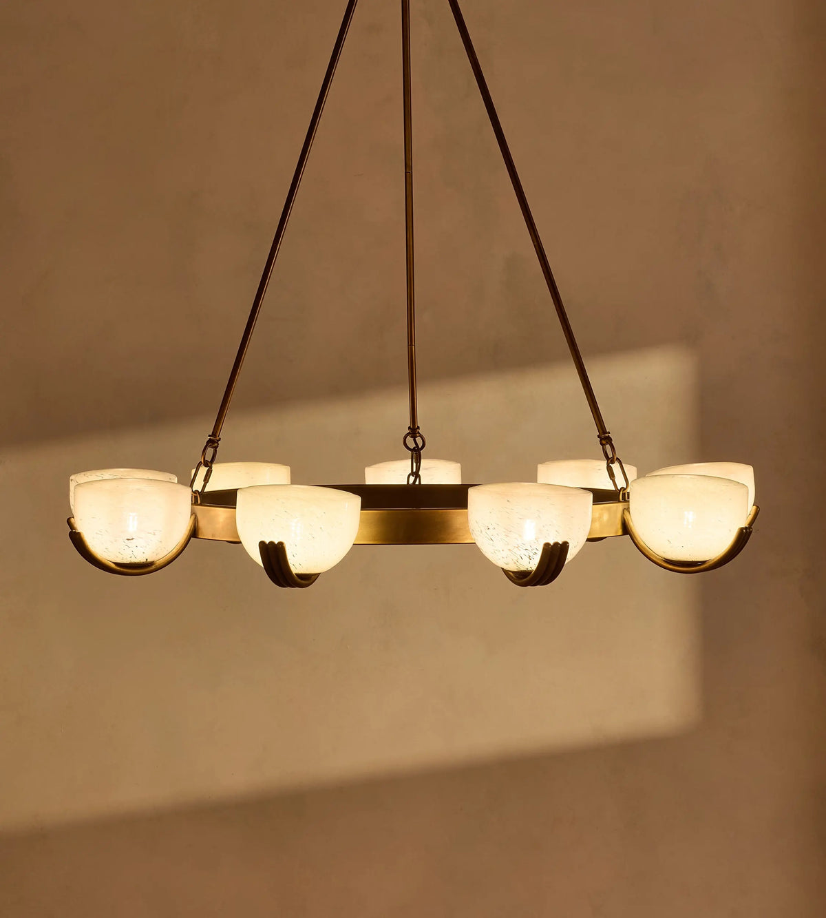 Elber chandelier illuminated with a warm glow against a neutral wall