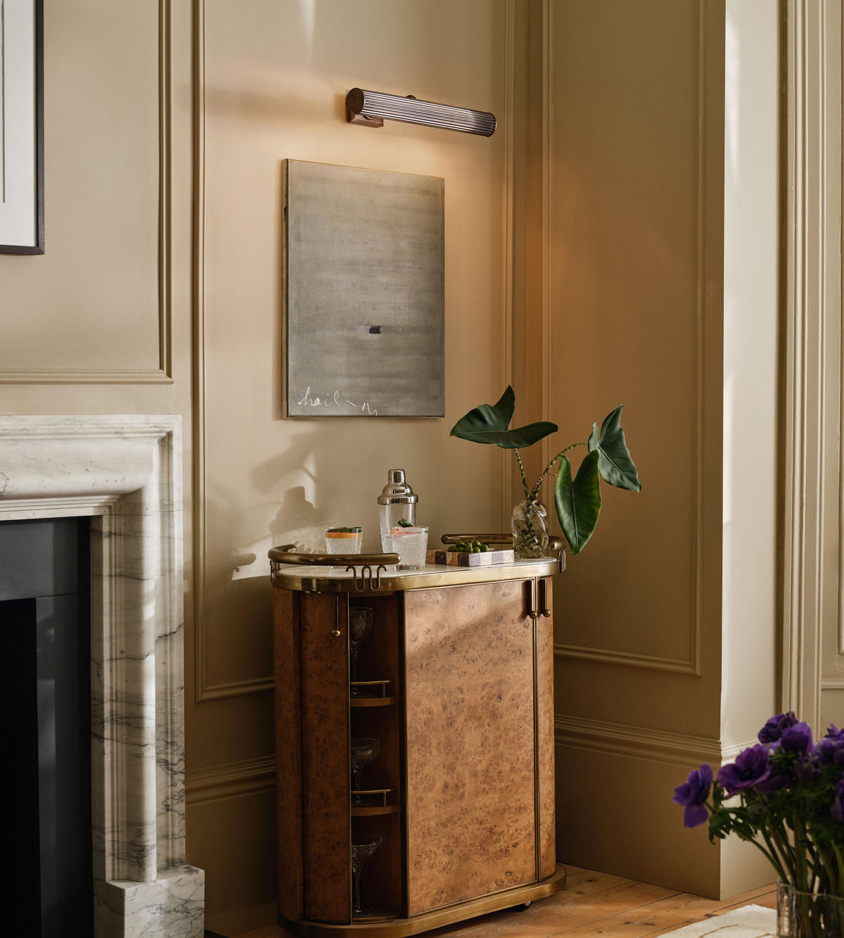 Ashby aged brass picture light illuminating artwork in an interior