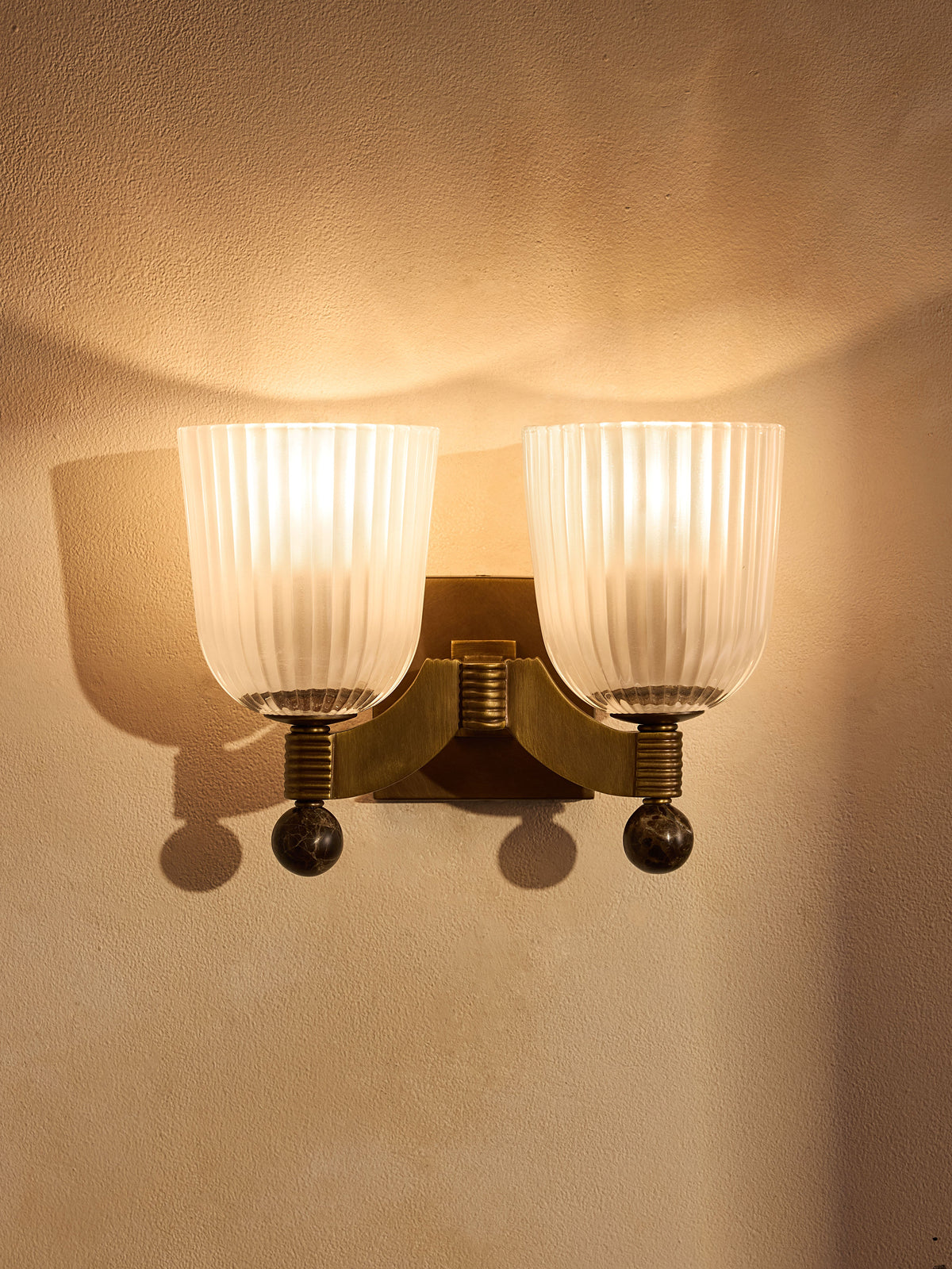 Colette wall sconce illuminated with two ribbed glass shades
