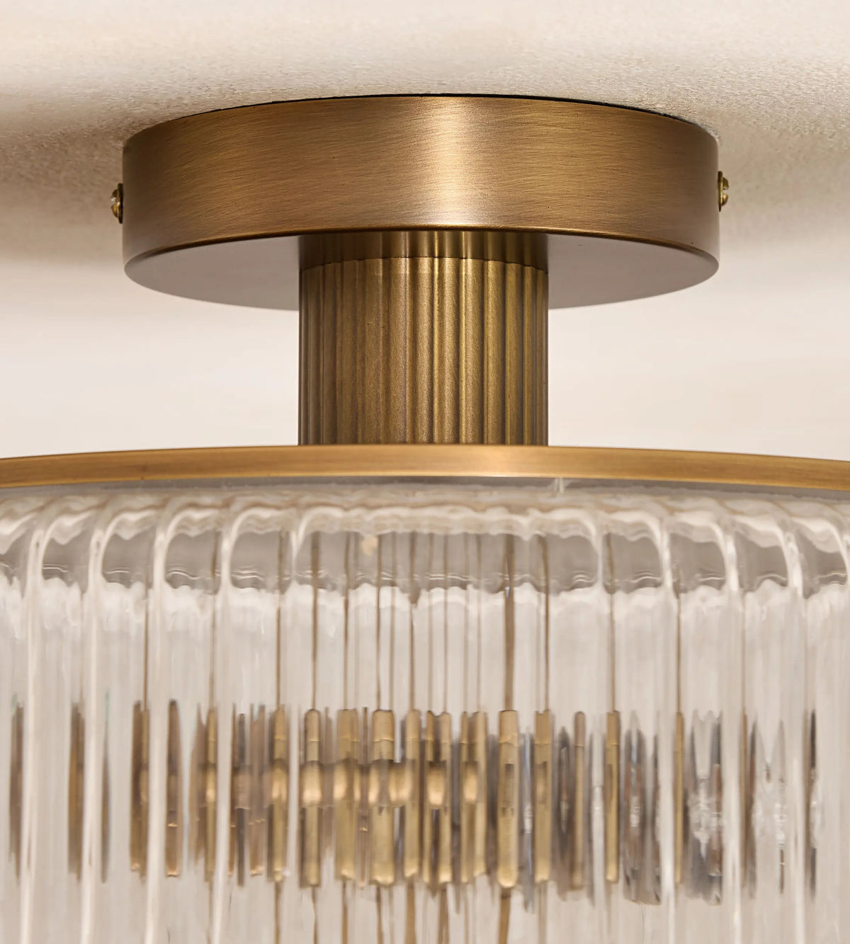 Close-up of Renato flush light antique brass ceiling mount and faceted glass