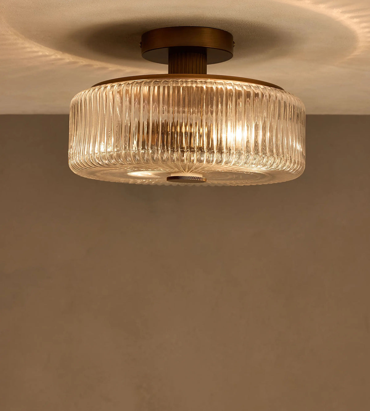 Renato ribbed glass flush ceiling light illuminated with a warm glow