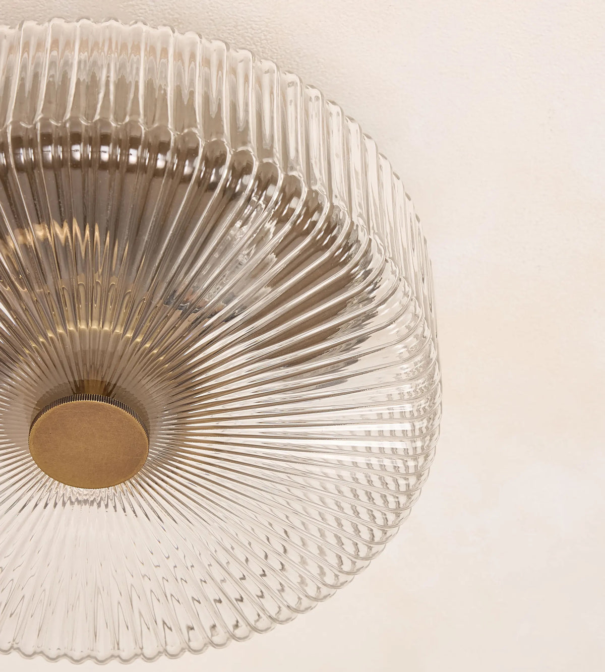 Detailed view of Renato flush mount ribbed glass shade and brass center cap
