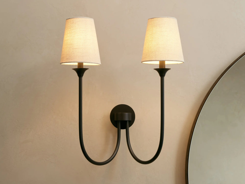 Saige bronze double wall sconce lit, front view with two off-white fabric shades