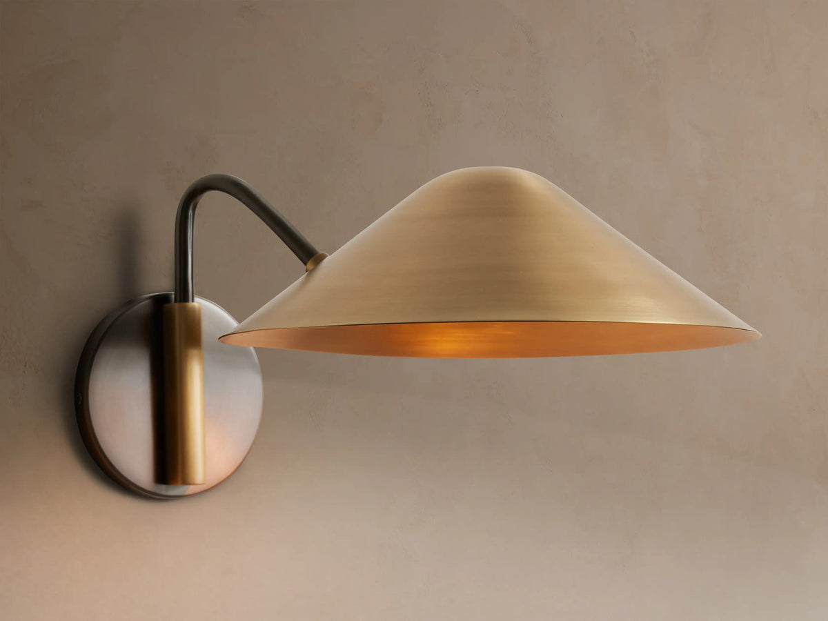 Simms brass wall sconce illuminated on a neutral wall