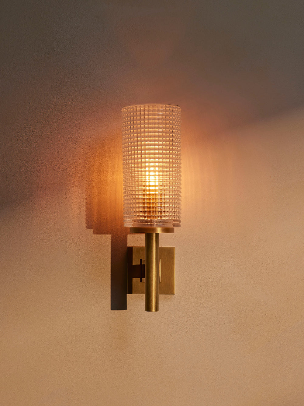 Skye ribbed glass wall sconce illuminated, front view