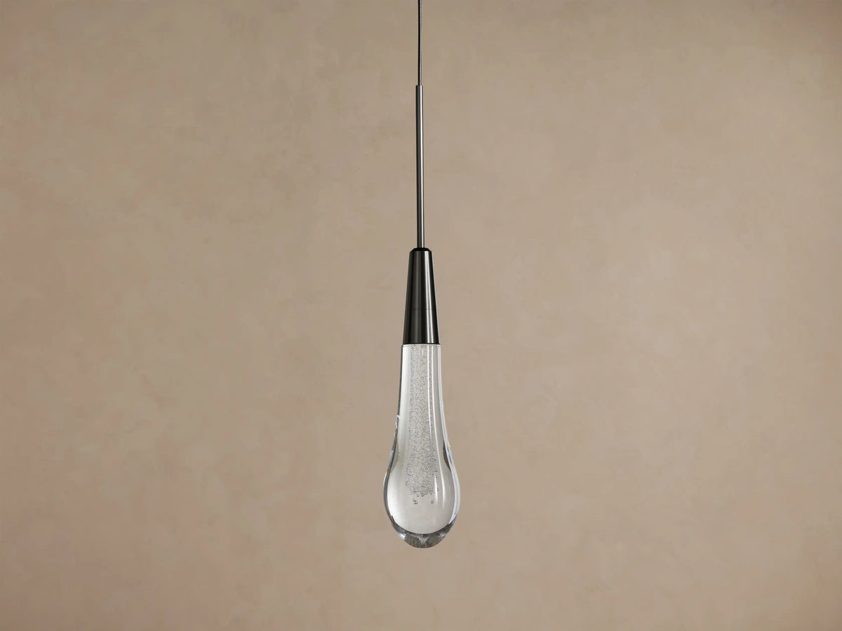 Soltaire bronze pendant glowing against a warm wall