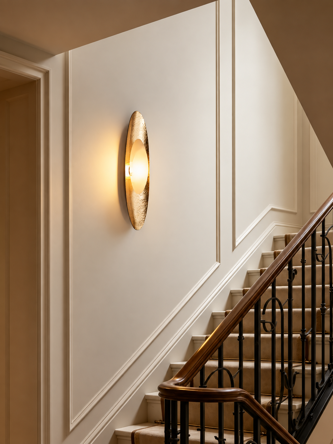 Gold and marble wall sconce lighting a staircase