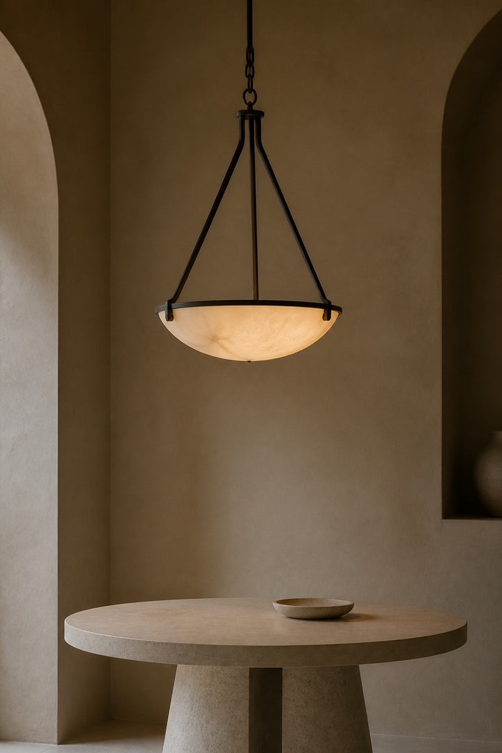 Alabaster pendant light with a warm glow above a stone dining table