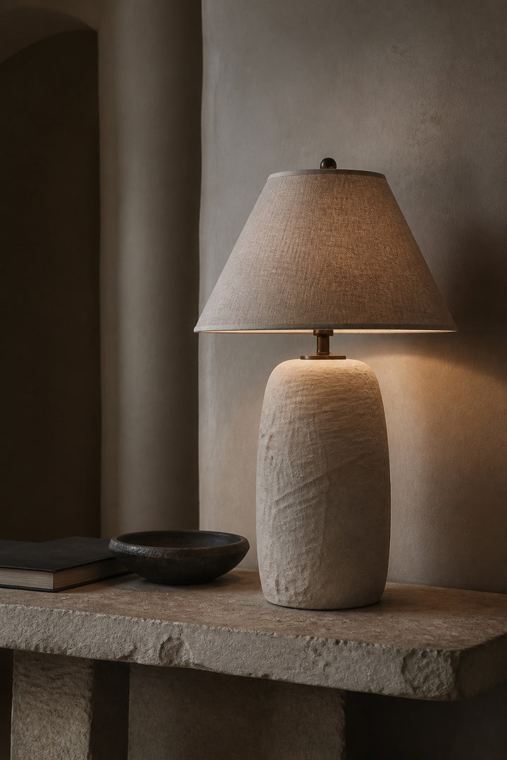 Sculptural alabaster table lamp with a linen shade on a natural stone console