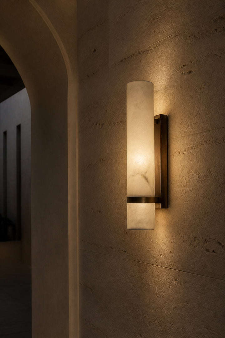 Alabaster wall sconce casting warm layered light on a textured stone wall